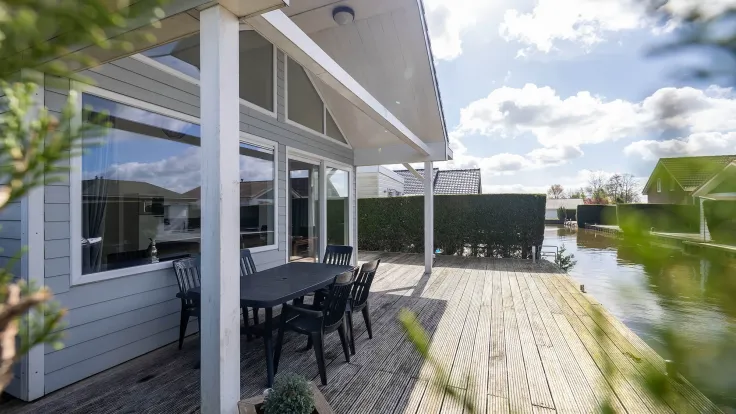 Vlonderterras met eettafel en stoelen direct aan het water bij de woning