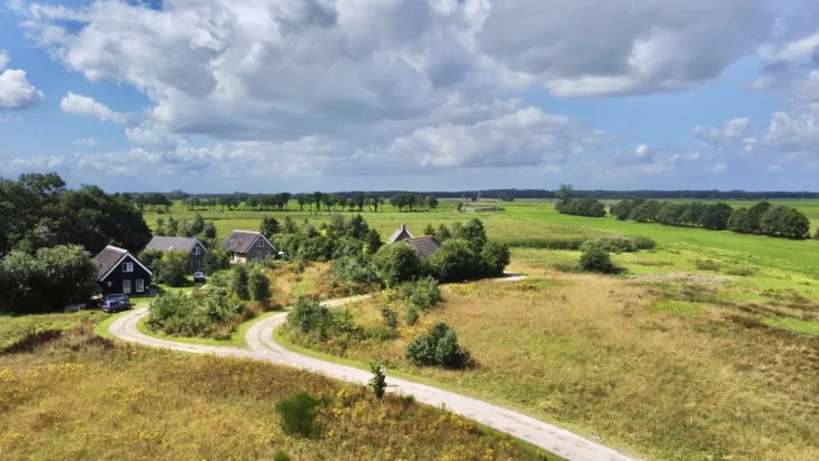 Luchtfoto van vakantiehuizen en een molen in het weidse landschap