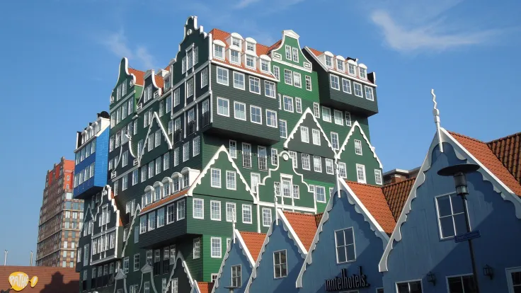Modern hotel opgebouwd uit groene Zaanse gevels tegen een blauwe lucht