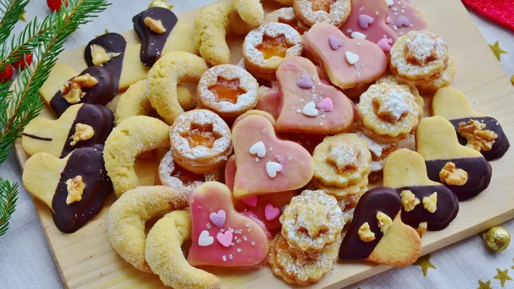 Zelfgemaakte kerstkoekjes met glazuur en decoratie op een houten plank