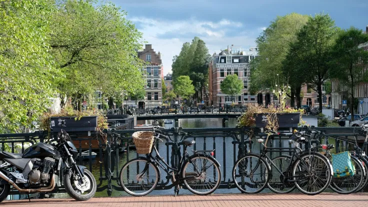 Gracht in Amsterdam met fietsen op de brugleuning en historische gevels