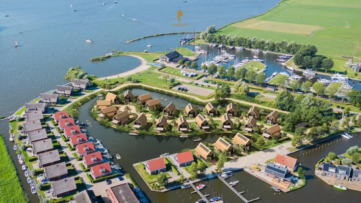 Luchtfoto van het vakantiepark met rieten daken, jachthaven en het meer