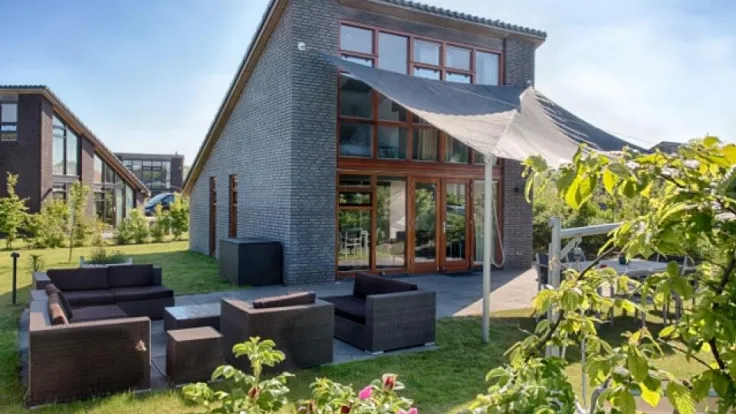 Modern gebouw met glazen pui en een loungeset in de tuin met rozen